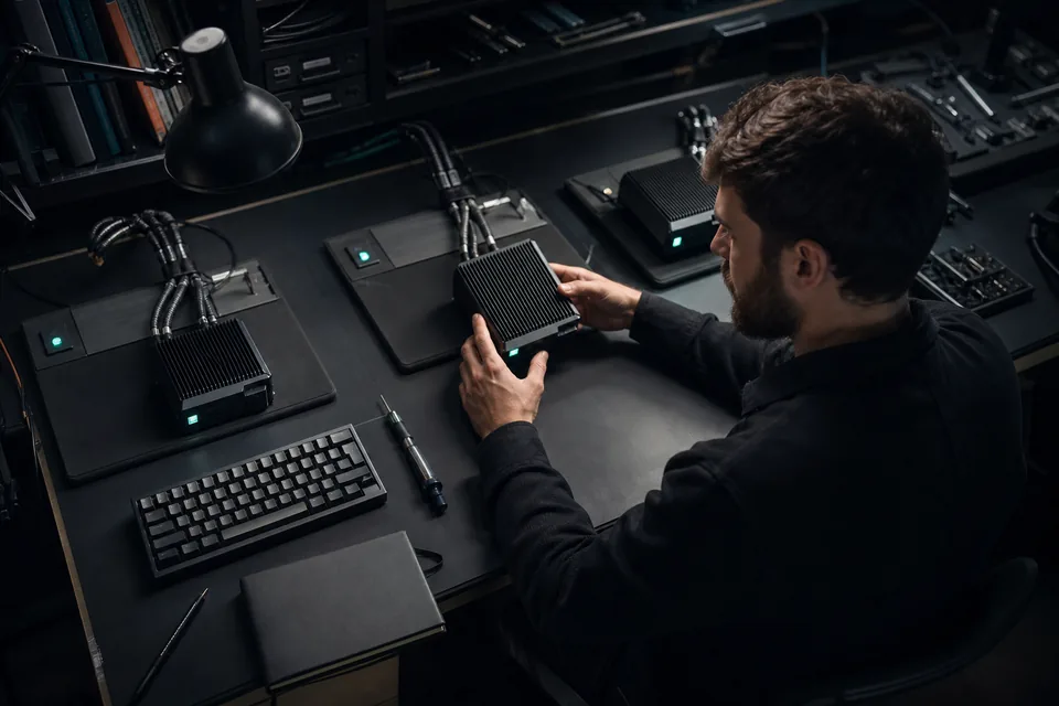 A developer reviews one compact compute module at a workbench with two isolated task stations.